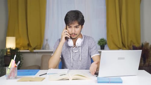 Young Adult Talking on Cellphone at Desk