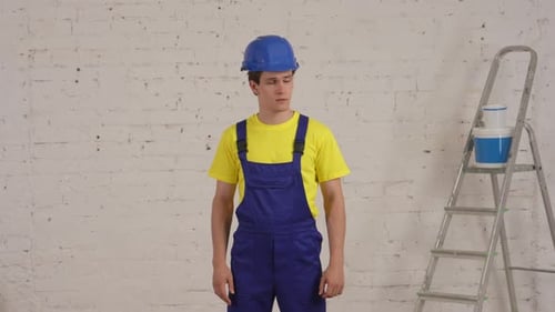 Man in Hard Hat Flexing Bicep in Front of Wall