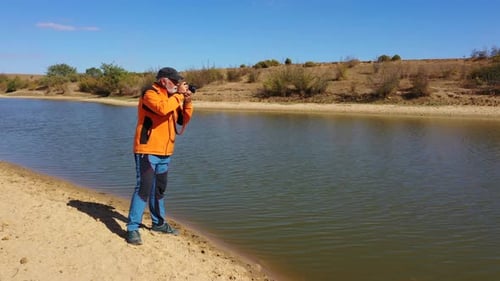 Man taking pictures at the edge of a lake