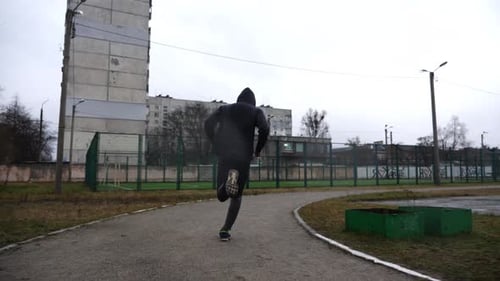 Young Sportsman Running on Path at Athletic Field in Cloudy Day Athletic Sporty Man Sprinting Fast