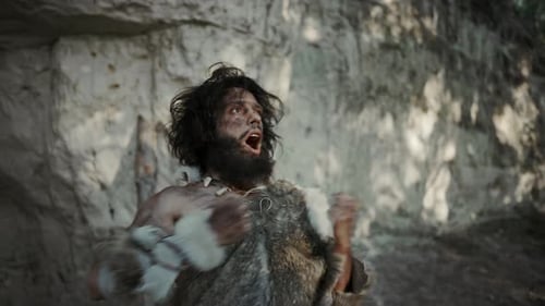 Retrato de un primitivo cavernícola vestido con piel de animal que amenaza con golpearse el pecho y gritar, Defe