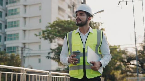 Portrait of Dreaming Engineer with Laptop and Coffee Walking Along Modern City