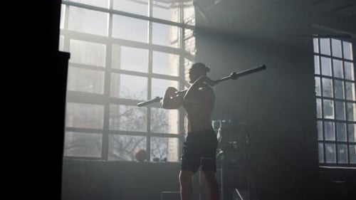 Muscular male bodybuilder doing front squats with barbell at modern gym workout
