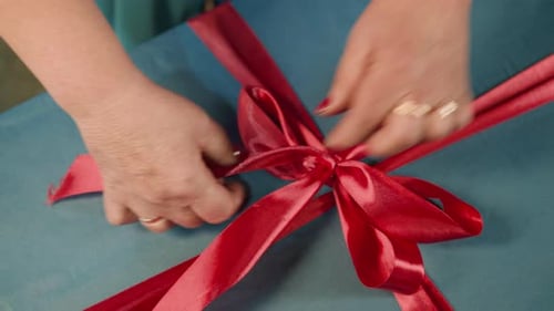 Hands Tying Red Bow on Gift Close Up