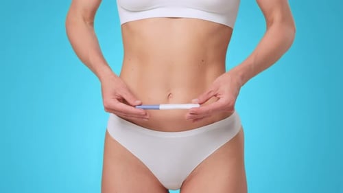 Woman Showing Pregnancy Test in a Bathroom With Blue Background