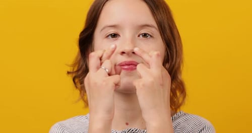 Teen Girl Fingers Crossed on Yellow Studio Background