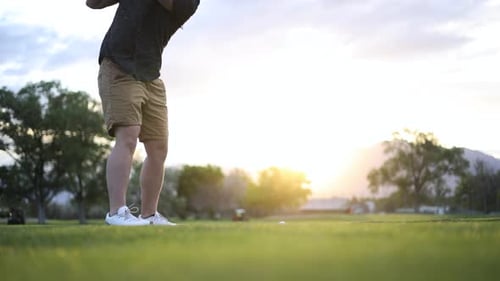 Golfer Swinging and Hitting Ball on Golf Course Fairway with Sun Flare