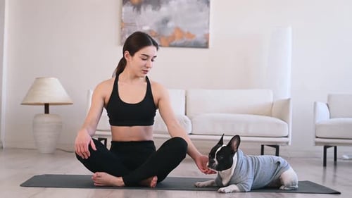 Woman Meditating with French Bulldog in Living Room