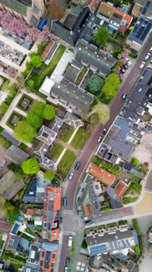 Aerial view of compact European neighborhood curved streets, red and gray rooftops, solar panels
