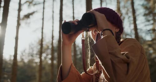 Young Woman with Binoculars in Sunny Forest