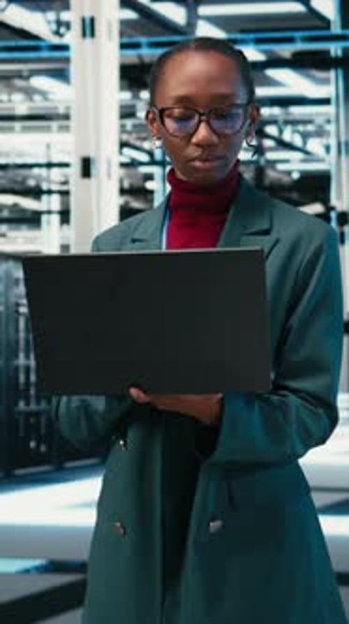 Vertical Video Managing Databases Laptop and Female Technician Walking in Data Center