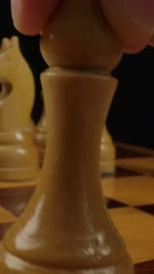 Vertical of Men's Hand Puts a Bishop Figure on Checkerboard Cell
