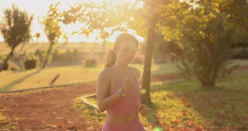 Active Woman Running Towards Camera in Park at Sunset