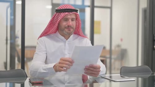 Arab Businessman Reviews Documents in Office