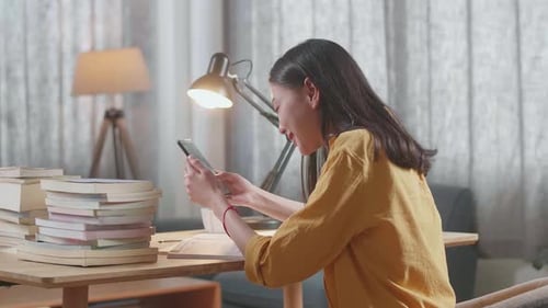 Young Woman Using Smartphone at Table with Books