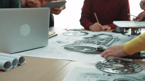 Collaborative Team of Engineers Discussing Mechanical Designs and Blueprints in a Bright Office Spac