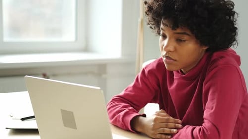 Sleepy African American Woman Sitting at Table with Laptop and Yawning