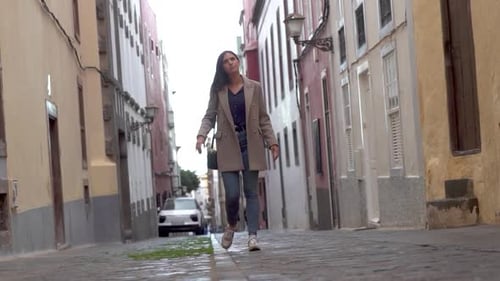 Woman walking through narrow street during winter with rain in Gran Canaria.