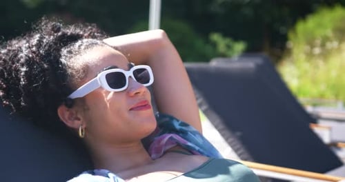 Woman reclining on lounge chair adjusting sunglasses as sunlight causing health HUD showing UV