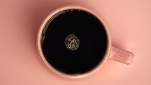 Top View of Cup with Black Coffee on Peach Background