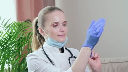 Woman Doctor Putting on Gloves and Face Mask