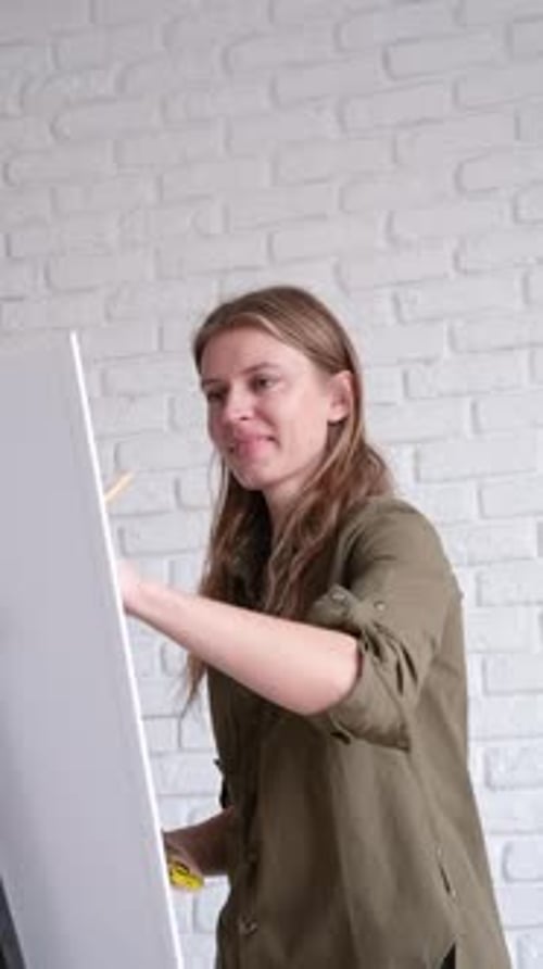 Smiling Woman Painting on Canvas Indoors