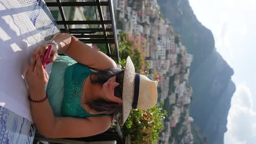 Vertical Portrait of Focused Female Tourist Using Smartphone on Amalfi Coast Sharing Photo on Social