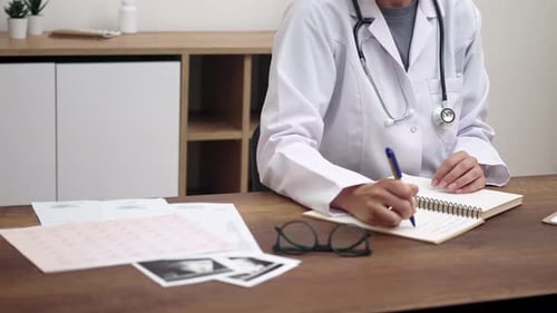 Doctor writing notes at office desk
