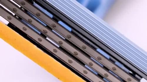 Close up view of a disposable shaver razor blade rotating on white background, shot in 4k.