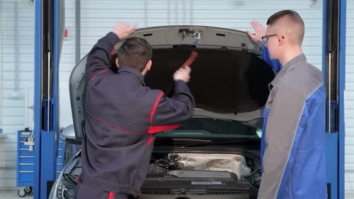 Deux mécaniciens inspectent le moteur d'une voiture à la station-service