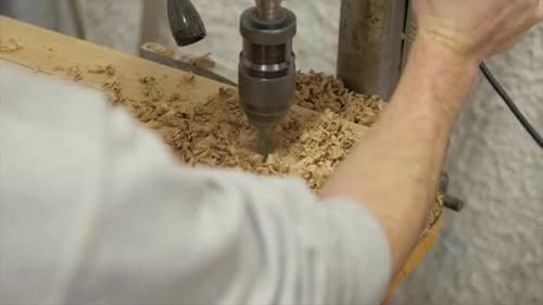 Pillar drill being used to drill holes in white oak slab. Medium close up