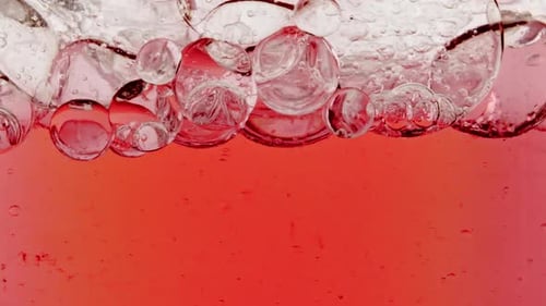Zeitlupe von sich bewegenden roten Öl- und Luftblasen im Wasser, die auf hellweißem Hintergrund aufsteigen
