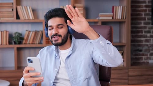 Jovem indiano alegre ouvindo música favorita em fones de ouvido sem fio