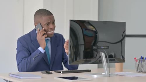 Frustrated Businessman Arguing on Phone at Desk