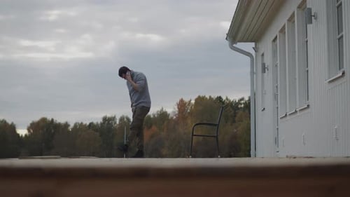 Casual man talking outside on moody day near his home, static view