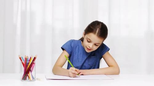 Girl drawing with colored pencil at white desk