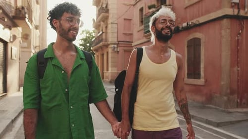 Gay tourist couple in love walks down street holding hands