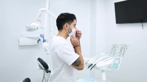 Male dentist putting on a surgical mask in a modern dental clinic.