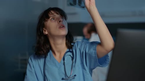 Medical Worker Examining X-Ray in Dark Room