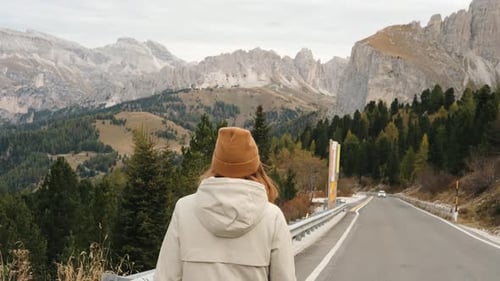 Tourist Redhead Woman Walking on Mountain Road Looking at Snowy Italian Alps