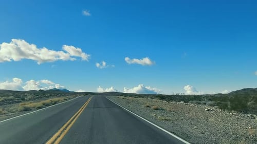 Open Road in the Desert A Deserted Highway Stretches Into the Horizon Under a Vast Blue Sky with