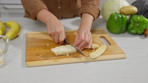 Person slicing a fresh banana on cutting board