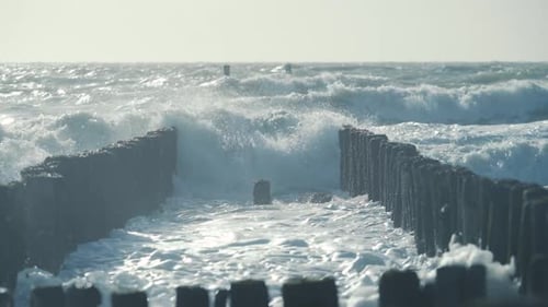 Sea waves slamming on wave breaker poles in the North sea, Zeeland. Rough weather strong winds. Medi