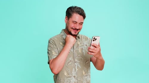Excited Man Using Smartphone Against a Blue Background