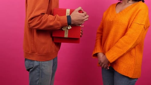 Man Giving Present to Woman on Pink Background