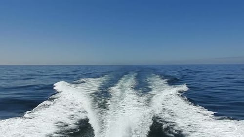 wake of water seen from behind of fast moving motor boat in a clear sky day,Blue sea , water surface