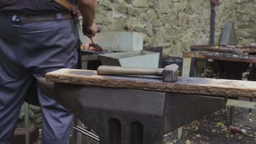 Close-up of a blacksmith’s anvil, hammer, and forge with flames, capturing the essence of traditiona