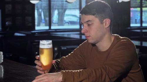 Cheerful Young Man Savoring a Refreshing Craft Beer at a Cozy Pub