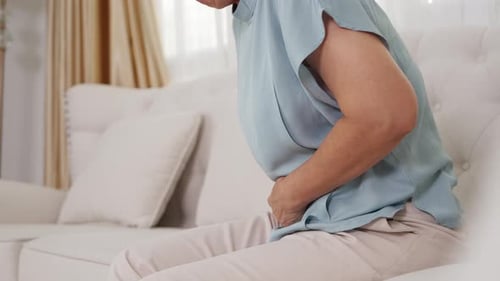 Elderly Woman Clutching Stomach in Discomfort
