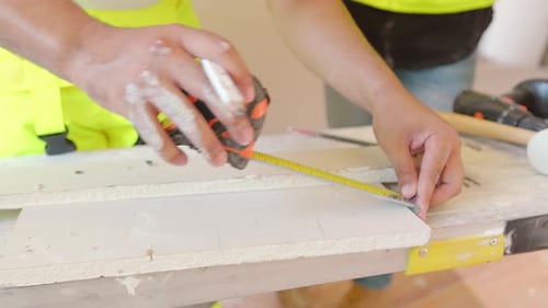 Construction Workers Engaging in the Process of Measuring and Marking Wood with Tools